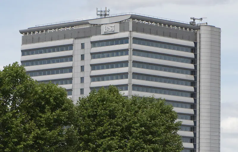 Tall office building with BSI lettering at the top, behind trees